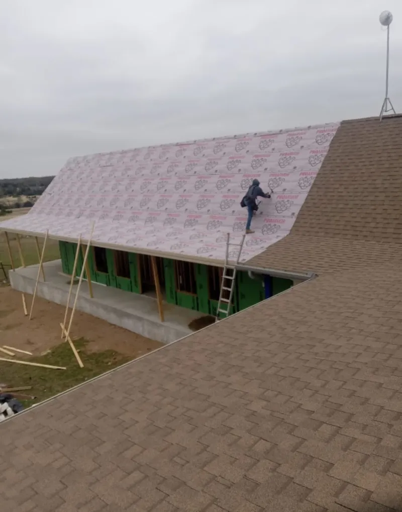 Worker preparing underlayment for a metal roof installation in San Angelo